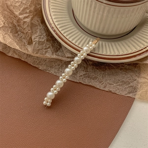 Macro detail of elegant pearl hair clip with gold metal base on vintage aesthetic background