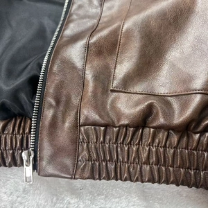 Dettaglio del bomber in pelle marrone scuro con trama vintage e cerniera metallica