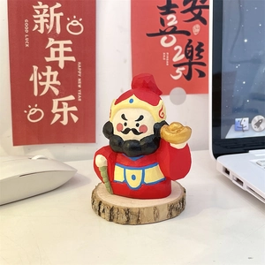 Close-up of God of Wealth figurine with gold ingot and natural wooden base for desk