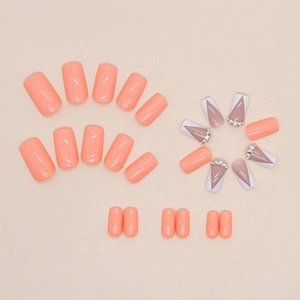 Faux ongles carrés orange avec pointes en V violettes et accents de strass
