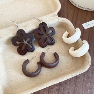 Détail de trois paires de boucles d'oreilles vintage en bois avec fleurs et formes en C