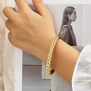 Detail of golden stainless steel link bracelet with watch band style on a model's wrist