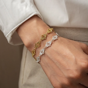Detail of hollow lace pattern bracelets in gold and silver finish worn by a model