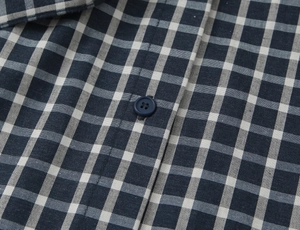 Detailed macro view of checkered shirt fabric with navy resin button and texture