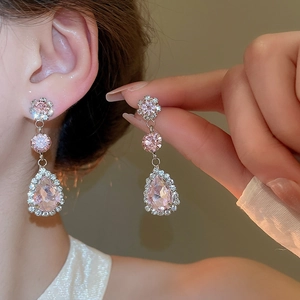 Close-up of pink crystal teardrop earrings with floral diamond accents on model