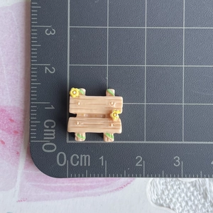 Detailed macro view of miniature dollhouse resin stool on a grey grid cutting mat