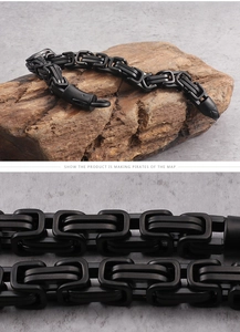 Close-up of matte black titanium steel chain bracelet on rustic wood and stone base