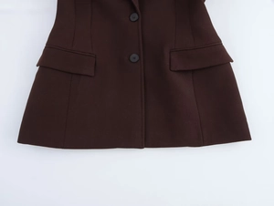 Detailansicht eines dunkelbraunen Blazers mit Reverskragen, zwei schwarzen Knöpfen und Taschen