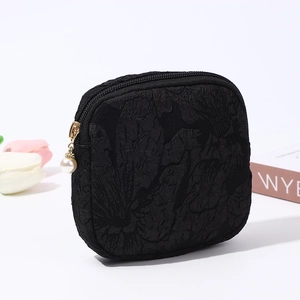 Close-up of black embossed floral canvas pouch with elegant pearl zipper detail