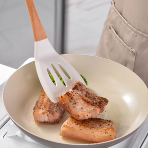 Silicone slotted turner with wooden handle for cooking meat in a stylish frying pan