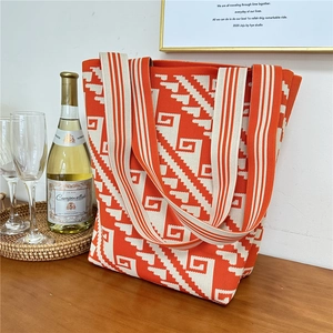 Detail of orange and beige knit tote bag with geometric pattern on a wooden table