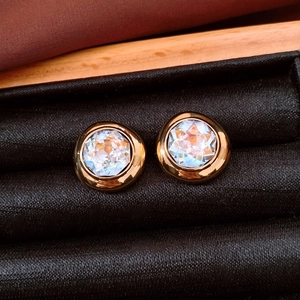 Macro shot of gold oval earrings with multifaceted crystals in a black velvet jewelry box