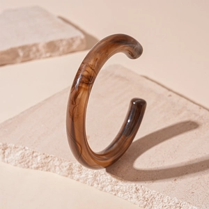 Macro detail of amber marble acrylic cuff bracelet with polished resin texture finish