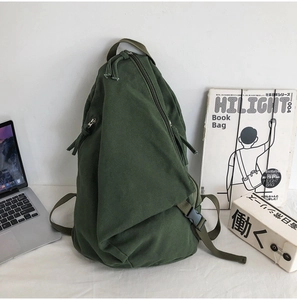 Detail of army green canvas backpack featuring unique triangular shape and buckle straps