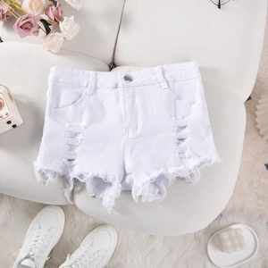 Flat lay of white distressed denim shorts with frayed hems and lifestyle accessories