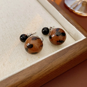 Close-up of vintage leopard print double bead earrings on a beige fabric tray