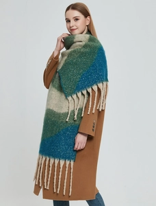 Detailed view of thick knit scarf with green and blue color blocks and tassels