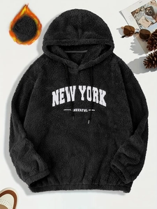 Dettaglio del ricamo New York sulla trama in pile nero della felpa con cappuccio