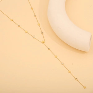 Close-up of gold Y-necklace with star pendants and sparkling zircons on stone