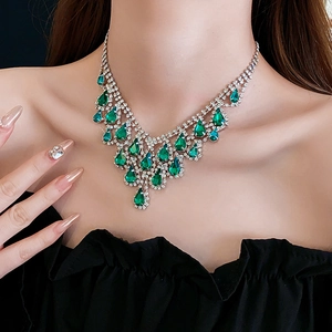 Detail of elegant silver necklace featuring green teardrop crystals and layered rhinestones