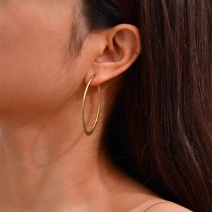 Classic large golden hollow heart hoop earrings shown on model for a trendy retro look