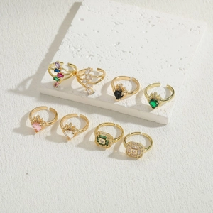 Primer plano de 8 anillos dorados con circonitas de colores en forma de corazón y cuadrado