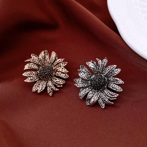 Detail of vintage sunflower brooches in antique gold and silver on silk fabric
