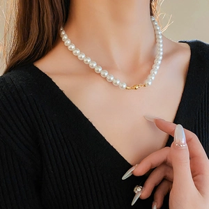 Close-up of elegant pearl necklace with a gold magnetic clasp worn by a model