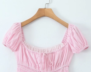 Close-up of pink and white striped dress featuring a square neck and smocked chest detail