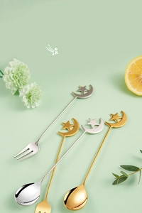 Detail view of gold and silver star and moon stainless steel dessert spoon and fork set