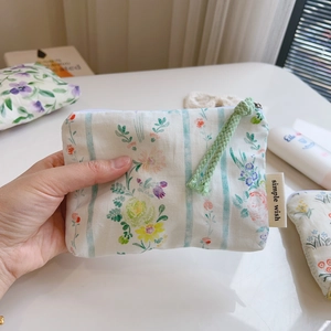 Floral cotton mini pouch with blue stripes and green zipper cord held by hand