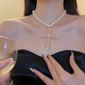 Close-up of pearl cross pendant necklace worn by a model in a luxury banquet setting