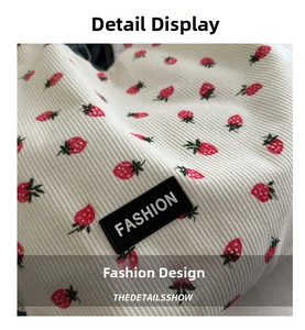 Detailed close-up of corduroy fabric with strawberry print and a fashion label
