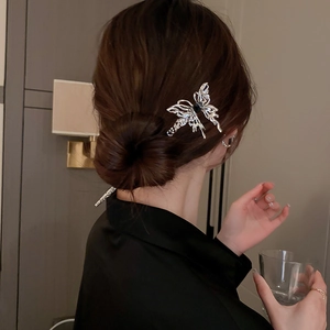Detailed close-up of a silver butterfly hair pin with hollow wings and black bead accents