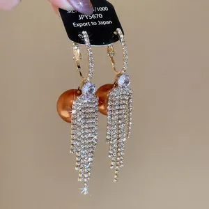 Elegant gold tassel earrings with shimmering crystals and a large bronze pearl accent