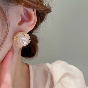Close-up of model wearing floral crystal and pearl earrings with champagne gold tones