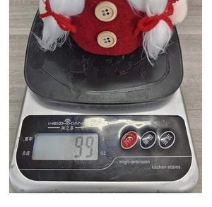 Gnome de Noël rouge pesant 99g sur une balance numérique, vue rapprochée détaillée