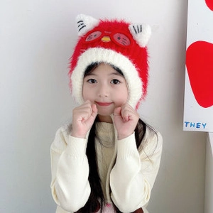Close-up of a red and white knitted children's hat with cute cat ears and embroidery