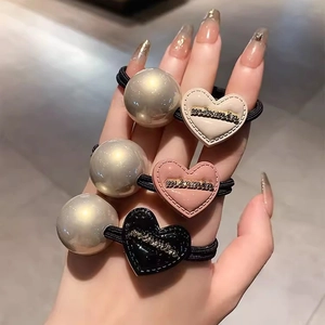 Trois élastiques à cheveux avec perles et breloques cœur en rose, beige et noir élégants
