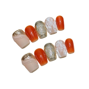 Short pumpkin orange press-on nails with gold foil and 3D textured accents
