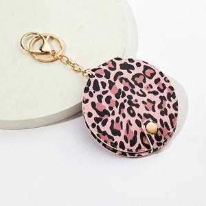 Pink leopard print keychain makeup mirror with golden metallic ring on white pedestal