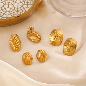Three pairs of vintage gold geometric earrings set on white silk and golden tray