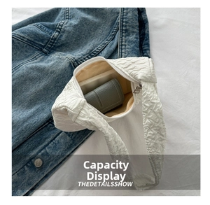 Interior view of white quilted shoulder bag showing capacity for wallet and phone