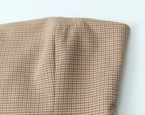Detaillierte Makroansicht des braunen Gingham-Gewebes mit präziser Mittelnaht-Verarbeitung