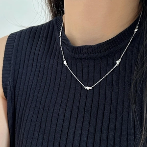 Detail of silver S925 multi-heart pendant necklace worn by a model on a black sweater