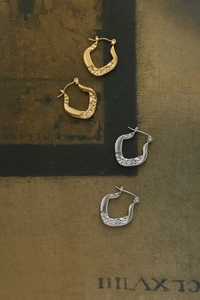 Detail of horseshoe hoop earrings with hammered texture in gold and silver finish