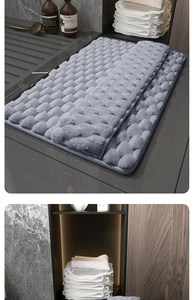 Close-up of grey memory foam bath mat with pebble texture in a modern shower room