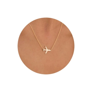 Détail d'un collier pendentif avion plaqué or 18 carats porté par un mannequin
