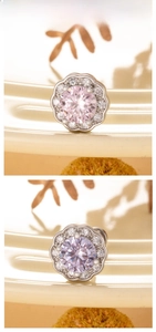 Detail of flower-shaped stud earrings with pink and purple zircon stones in a macro view
