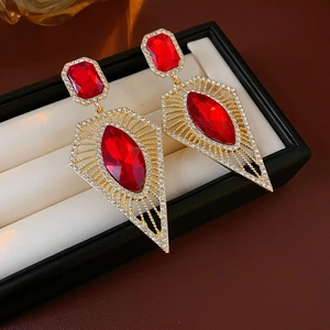 Detail of vintage gold earrings with red faceted gemstones and white pavé diamonds